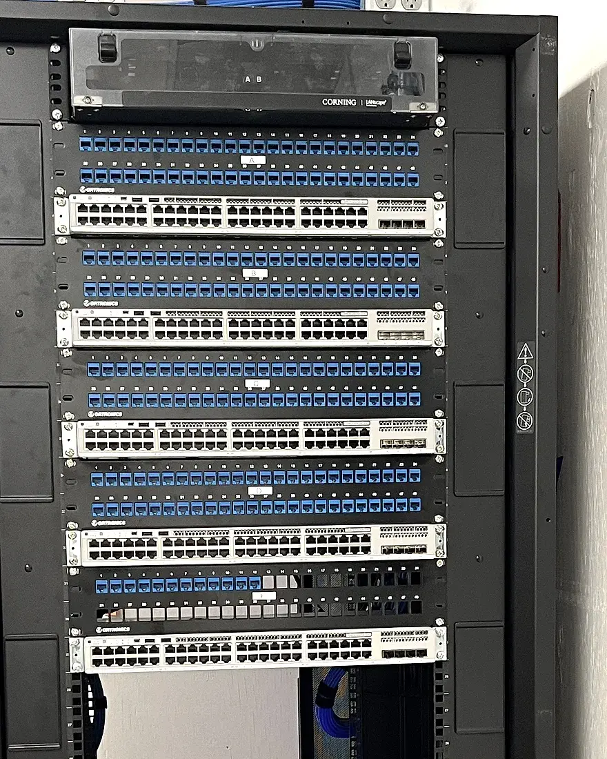 A stack of switches and patch panels in a finished floor rack